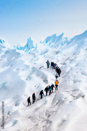 grupo de personas en fila subiendo por el hielo hacia la sima del glaciar Perito Moreno, en la patagonia Argentina