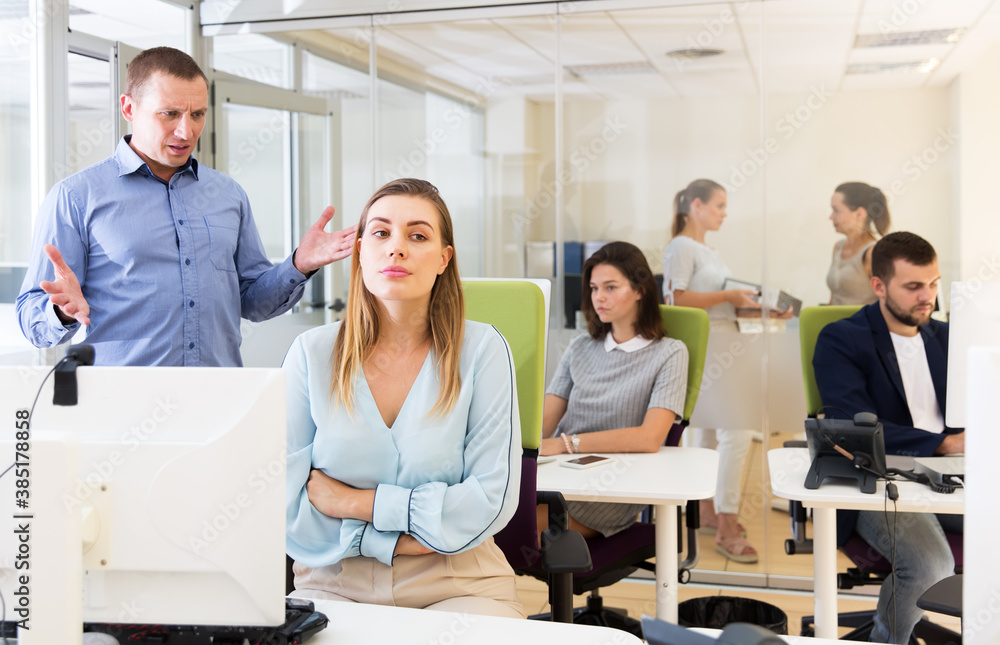Outraged businessman expressing dissatisfaction with work of frustrated young woman in modern office