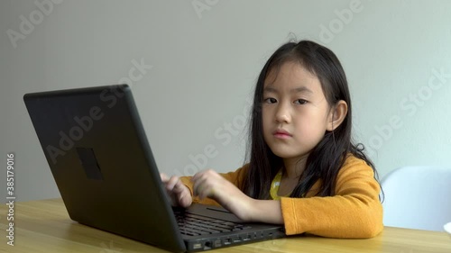 Cute little girl is boring to do homework with a computer