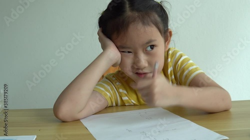 Cute smart primary school child girl learning writing doing math homework sit at home table, adorable pretty little preschool kid studying alone making notes, children elementary education concept