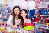 woman and vigorous daughter with gifts and balloons in the toys shop