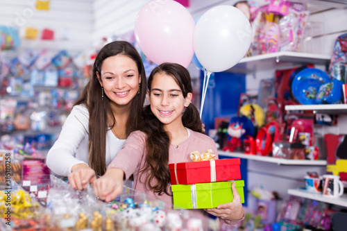 woman and vigorous daughter with gifts and balloons in the toys shop