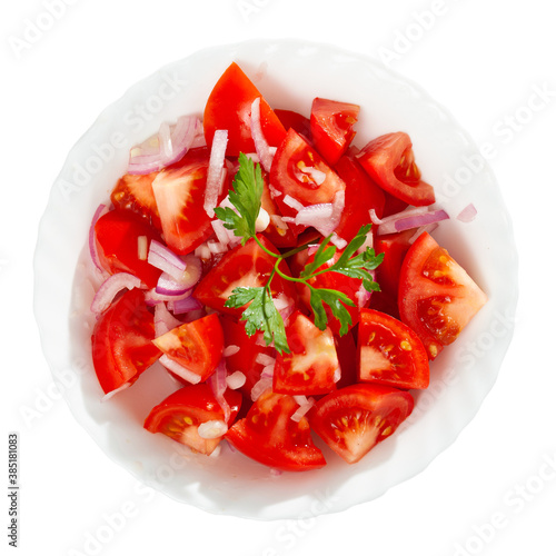 Vegetarian salad with tomatoes, onion, greens and olive oil at plate. Isolated over white background