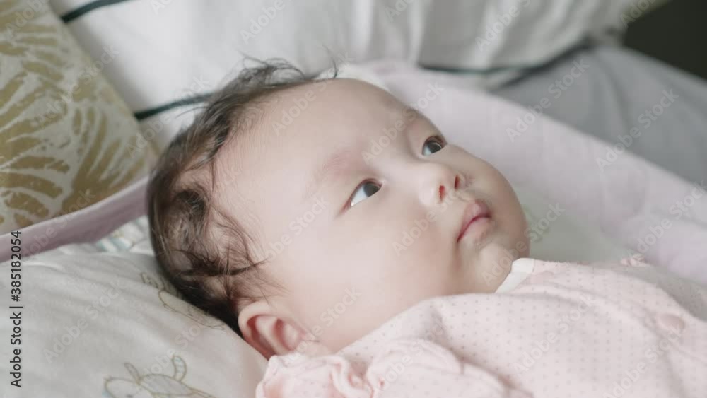 Medium-close reverse shot of a 2 month old mixed Korean baby lying in bed happily watching an electronic mobile rotate. Medium-close reverse shot of a 2 month old mixed Korean baby lying in bed happily watching an electronic mobile rotate.