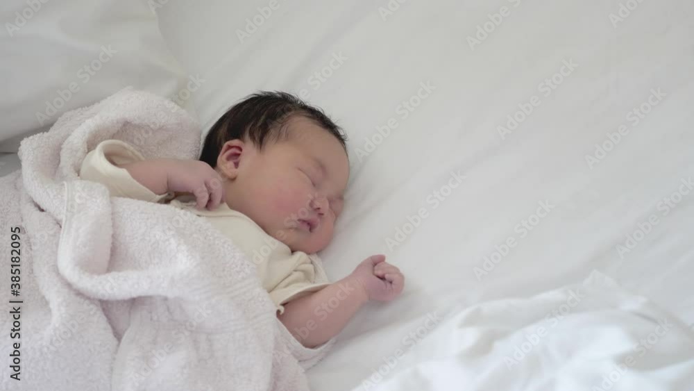New born mixed asian baby sleeping and dreaming on white sheets. New born mixed asian baby sleeping and dreaming on white sheets.