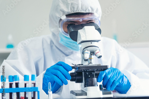 Male Scientist look into Microscope research in science laboratory. Asian scientist looking equipment laboratory chemistry labs. Covid-19 coronavirus biochemistry research experiment vaccine concept