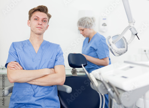Portrait of professional male dentist with arms crossed with dental assistant background. High quality photo