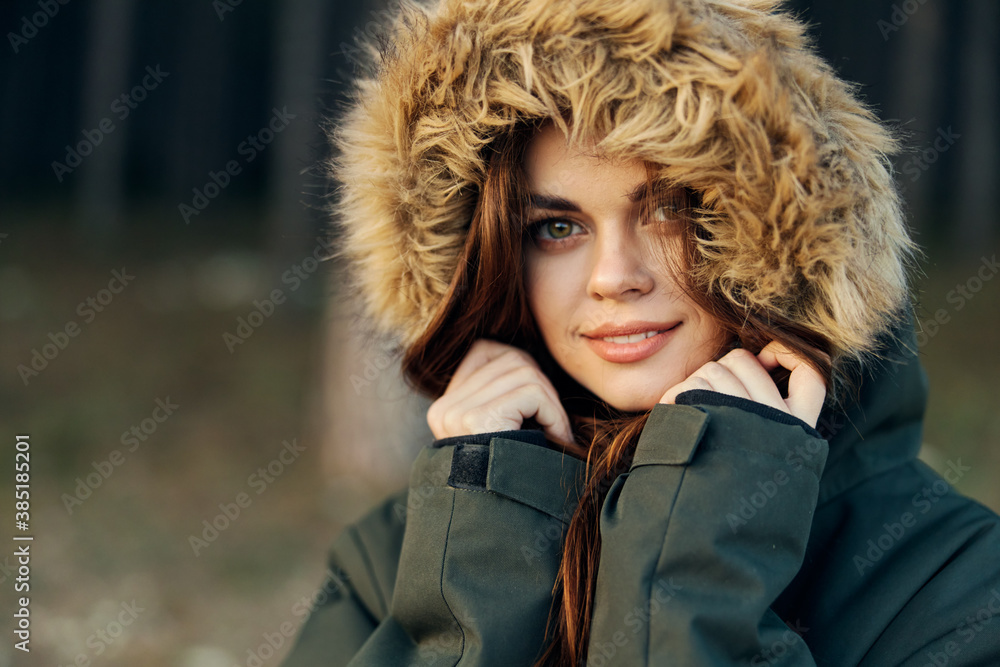 Pretty woman in a warm jacket with a hood in nature close-up Pretty woman in a warm jacket with a hood in nature close-up