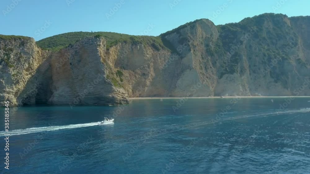 Aerial drone profile view chasing boat along cliff on Mediterranean / Ionian sea coast of the Greek Island of Corfu / Korfu / Kerkyra on a sunny day Paleokastritsa / Palaiokastritsa beach Aerial drone profile view chasing boat along cliff on Mediterranean / Ionian sea coast of the Greek Island of Corfu / Korfu / Kerkyra on a sunny day Paleokastritsa / Palaiokastritsa beach