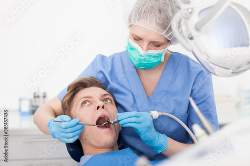 Male patient sitting on chair in dental office getting dentist treatment. High quality photo