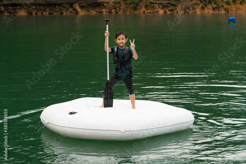 Family wearing life jackets paddling on an inflatable boat in Kenyir Lake, Malaysia.