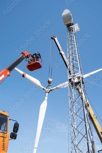 Construction of a wind power plant. Installers use a truck crane and aerial platform to raise the wind turbine rotor. Photo taken on a sunny summer day in Russia