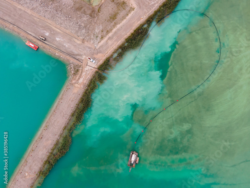 Photography Aerial drone view of colorful turquoise blue mining tailings with vehicles and b