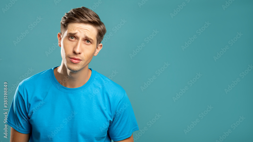 Confused male portrait. Puzzled face. Misunderstanding emotion. Doubtful young man looking at camera isolated on blue copy space. Confused male portrait. Puzzled face. Misunderstanding emotion. Doubtful young man looking at camera isolated on blue copy space.
