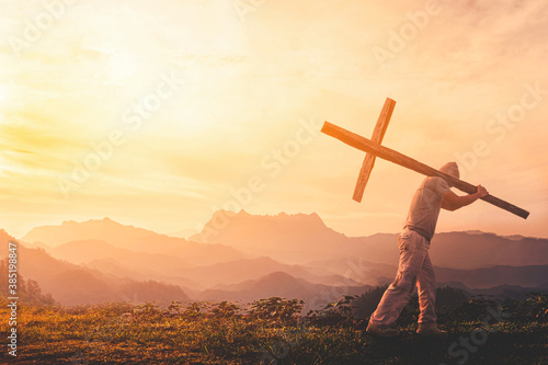 Silhouette of human carry cross on mountain sunset