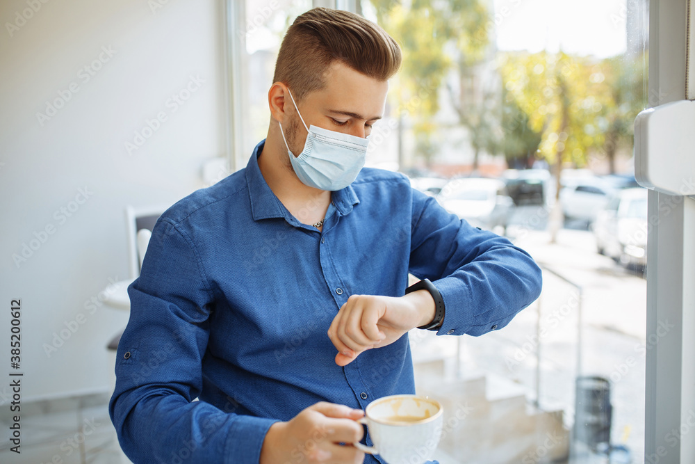Man working from a cafe checking time on his watch and drinking coffee ...