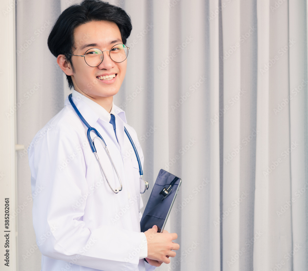 Portrait closeup of Happy Asian young doctor handsome man smiling in uniform and stethoscope neck strap holding smart digital tablet on hand and looking to the camera, healthcare medicine concept Portrait closeup of Happy Asian young doctor handsome man smiling in uniform and stethoscope neck strap holding smart digital tablet on hand and looking to the camera, healthcare medicine concept
