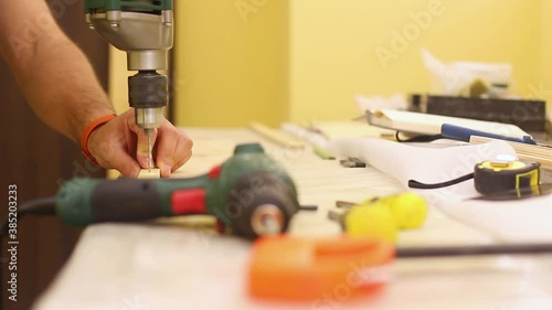 Wallpaper Mural Carpenter is working making furniture in workshop. Close up of wood worker using an electric hand drill to drill a hole through the chipboard.
 Torontodigital.ca
