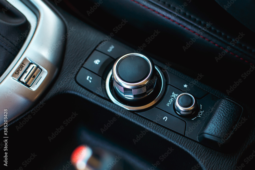 modern car media and navigation control buttons and regulator. black leather with red line interior details. close up
