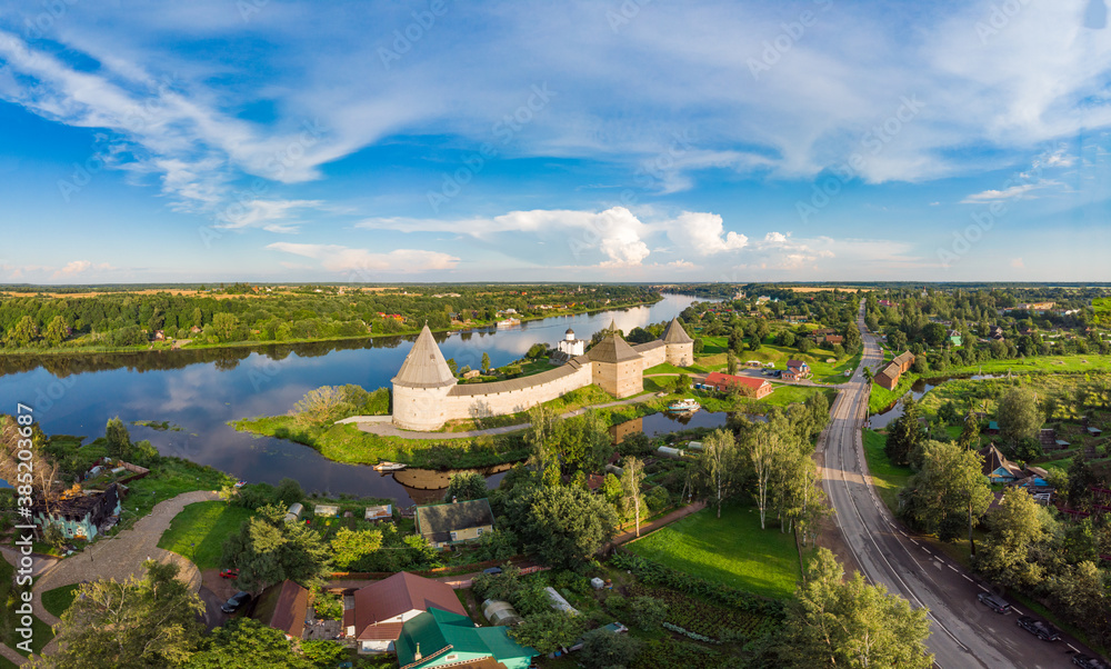 Aerial panoramic view of famous medieval fortress in Staraya Ladoga at sunset. Ancient Russian historical fort on Volkhov River on a sunny summer day. Europe, Russia, Leningrad region, St. Petersburg.