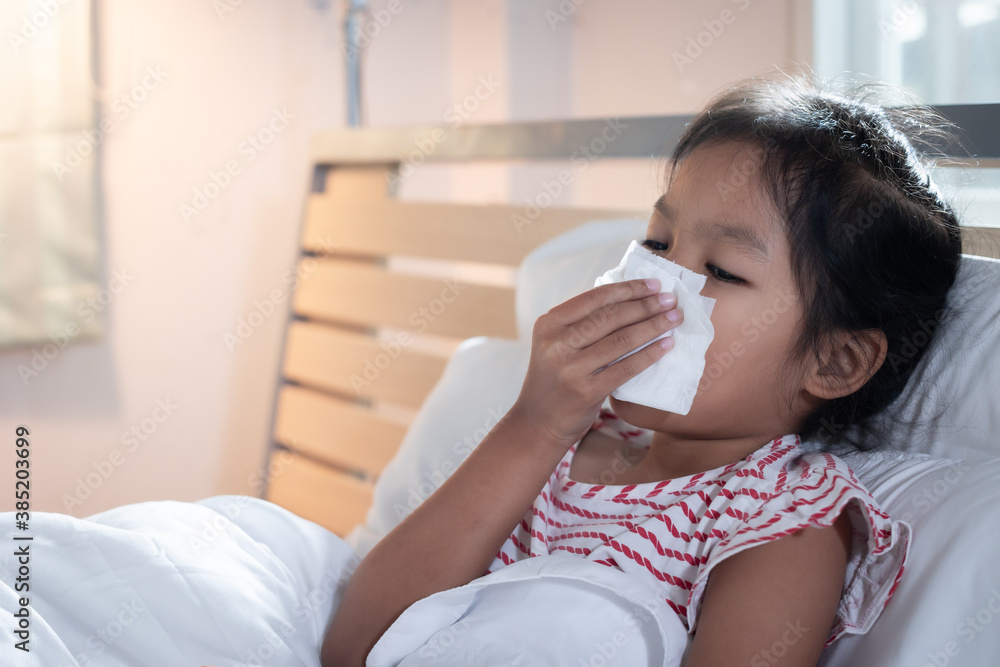 Asian child girl get sick ,coughing and sneezing. She is wiping nose with paper tissues. Sick child and health care concept. Asian child girl get sick ,coughing and sneezing. She is wiping nose with paper tissues. Sick child and health care concept.