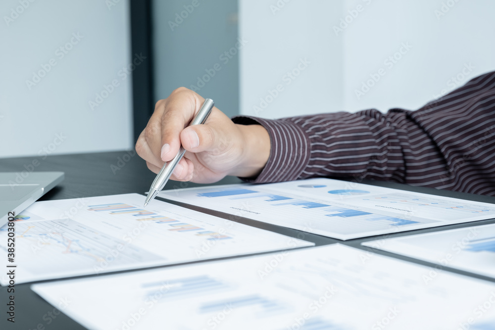 The hands of a male businessman are analyzing and calculating the annual income and expenses in a financial graph that shows results To summarize balances overall in office The hands of a male businessman are analyzing and calculating the annual income and expenses in a financial graph that shows results To summarize balances overall in office