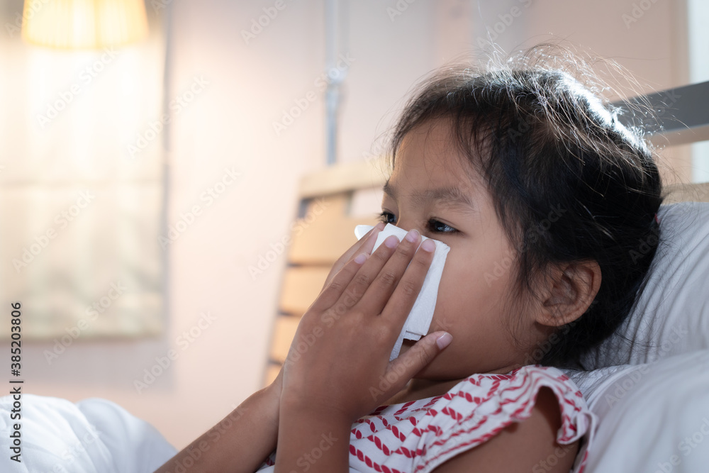 Asian child girl get sick ,coughing and sneezing. She is wiping nose with paper tissues. Sick child and health care concept. Asian child girl get sick ,coughing and sneezing. She is wiping nose with paper tissues. Sick child and health care concept.