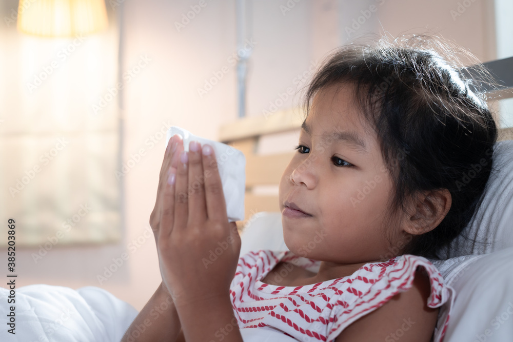 Asian child girl get sick ,coughing and sneezing. She is wiping nose with paper tissues. Sick child and health care concept. Asian child girl get sick ,coughing and sneezing. She is wiping nose with paper tissues. Sick child and health care concept.