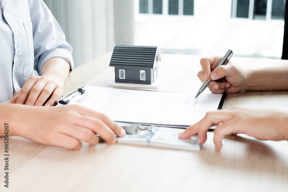 Fototapeta premium A real estate agent with rental homes and home insurance for clients to sign contracts under a formal home lease agreement. Home rental and insurance concept