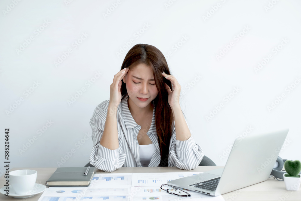 Working Asian women feel stressed, tired from work, migraine headaches from hard work while working at the office Working Asian women feel stressed, tired from work, migraine headaches from hard work while working at the office