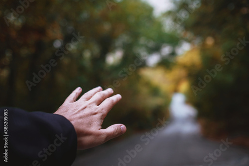 Autumn mood concept, men's hand and road perspective