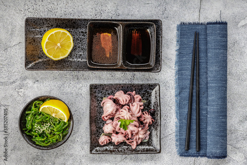 Traditional japanese or seafood concept. Delicious and healthy boiled mini octopus and wakame or seaweed salad with soy sauce and lemon served with chopstick.