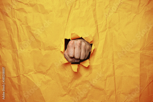 Faust Hand boxt durch Papier, orange photo