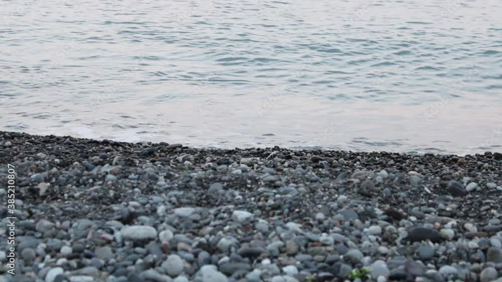 An empty pebble beach with waves on the shore near the city of Sochi Russia on a summer baking day. An empty pebble beach with waves on the shore near the city of Sochi Russia on a summer baking day.