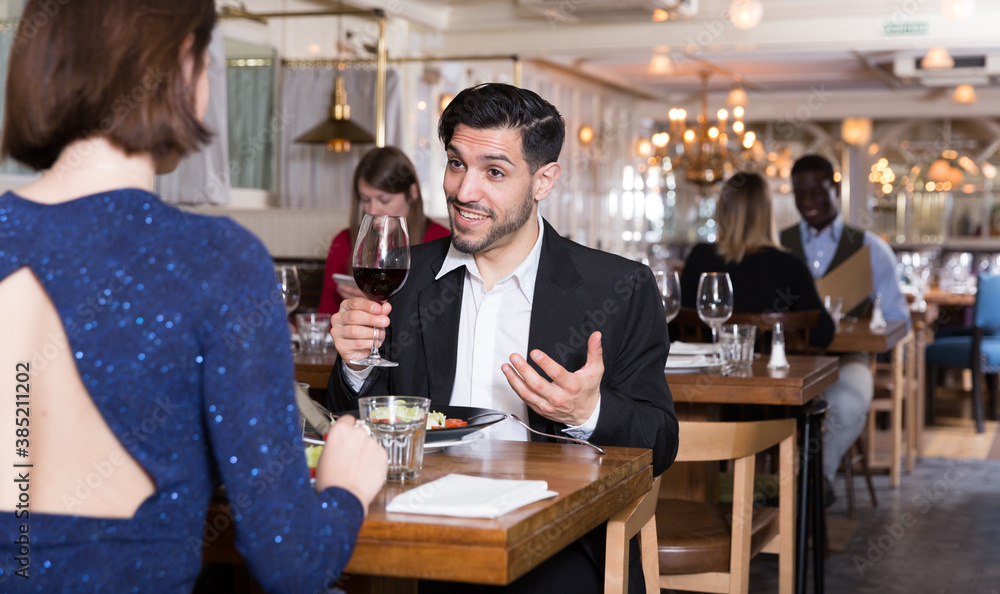Smiling bearded man with female colleague on friendly meeting over dinner in restaurant