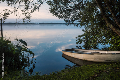 nice landscape with a small sailboat by a lake at dawn