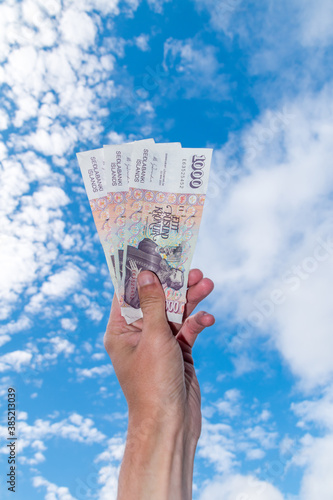 Human hand hold 1000 ISK banknotes. Icelandic krona bills on sky background.