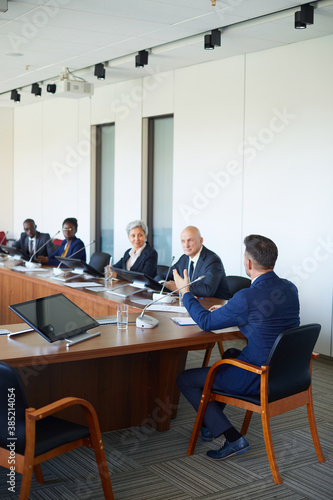 Rear view of businessman talking to his colleagues while they sitting at the table at board room