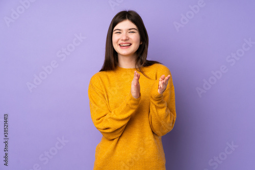 Young Ukrainian teenager girl over isolated purple background applauding after presentation in a conference © luismolinero
