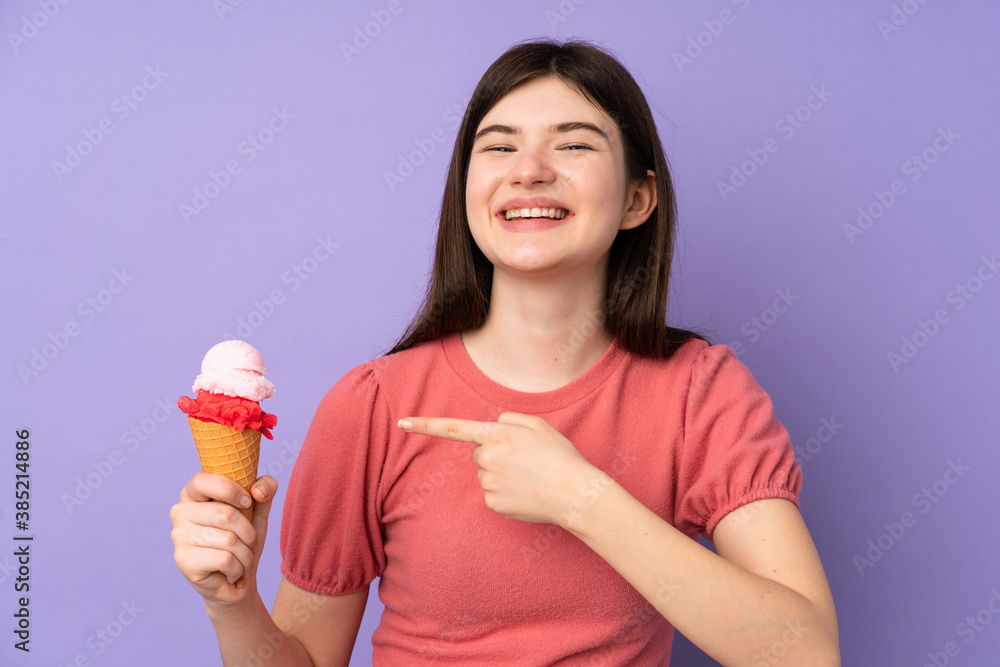 Young Ukrainian teenager girl holding a cornet ice cream over isolated purple background and pointing it Young Ukrainian teenager girl holding a cornet ice cream over isolated purple background and pointing it