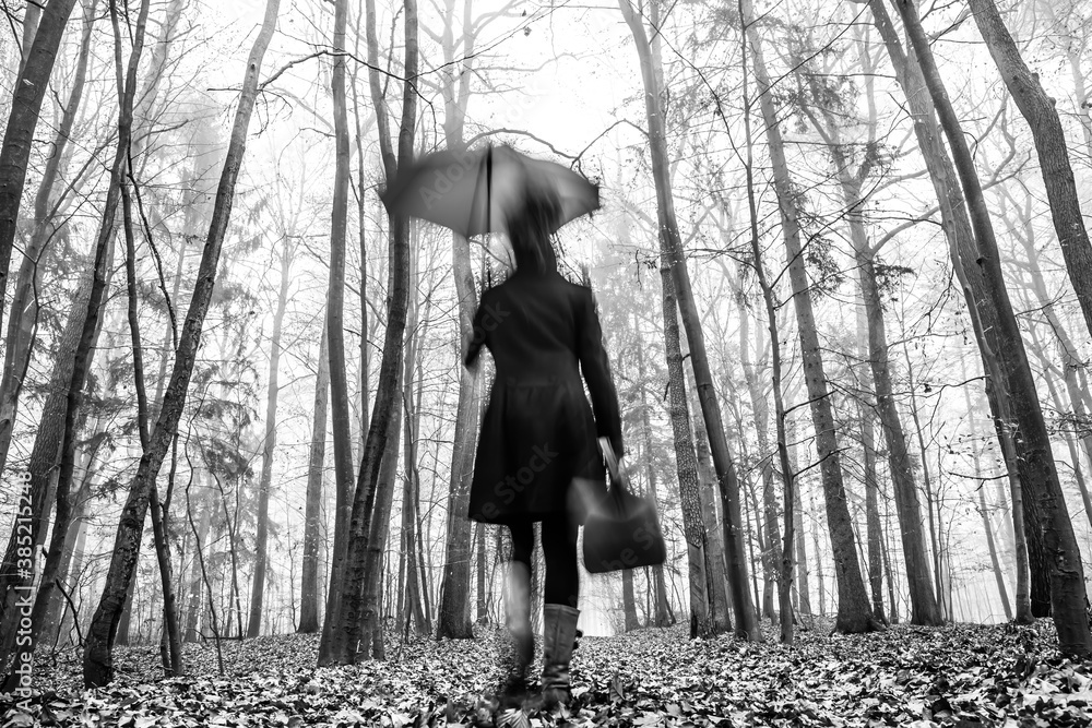 A woman is walking quickly through a misty autumn forest A woman is walking quickly through a misty autumn forest