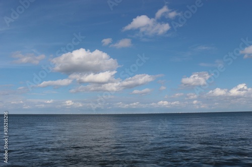 Sea and sky: The rivermouth of the Elbe at high tide in Cuxhaven. Here the Elbe river flows into the North Sea. Far in the distance a wind park is to be perceived. North Germany, Europe.