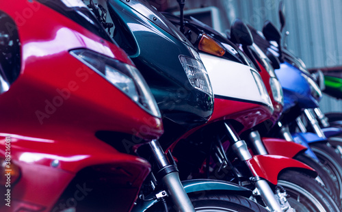 Many modern road bikes lined up stand in shop for sale. Headlights of sports motorcycles, in showroom in store. Maintenance, repair of motorcycle equipment in garage. Service, old photo