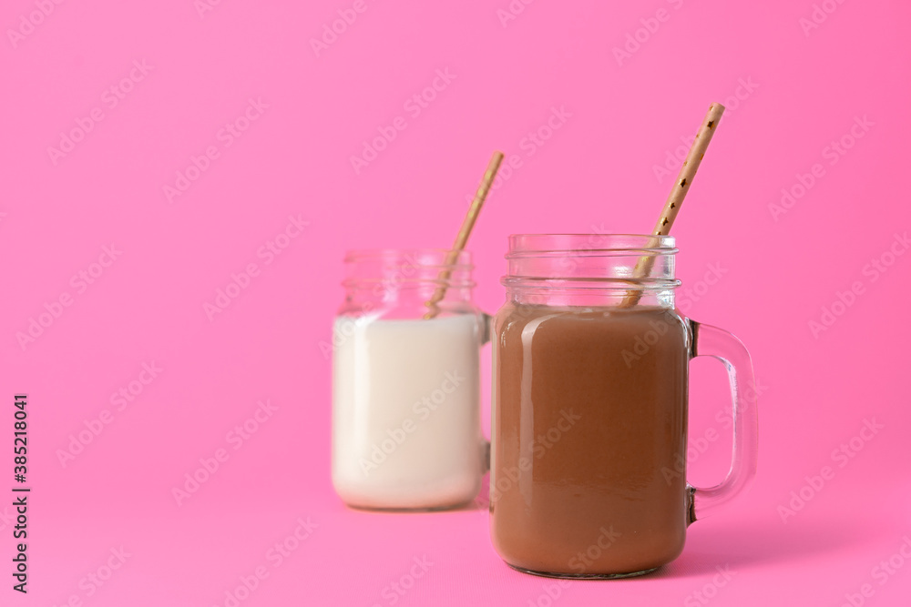 Glass jars with flavoured milkshakes against pink background Glass jars with flavoured milkshakes against pink background