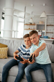 Happy brothers playing video games. Young brothers having fun while playing video games in living room
