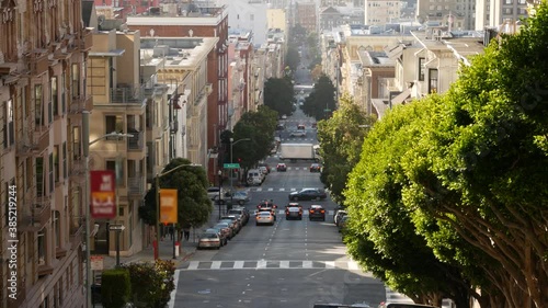 Iconic hilly street and crossroads in San Francisco, Northern California, USA. Steep downhill road and pedestrian walkway. Downtown real estate, victorian townhouses abd other residential buildings.