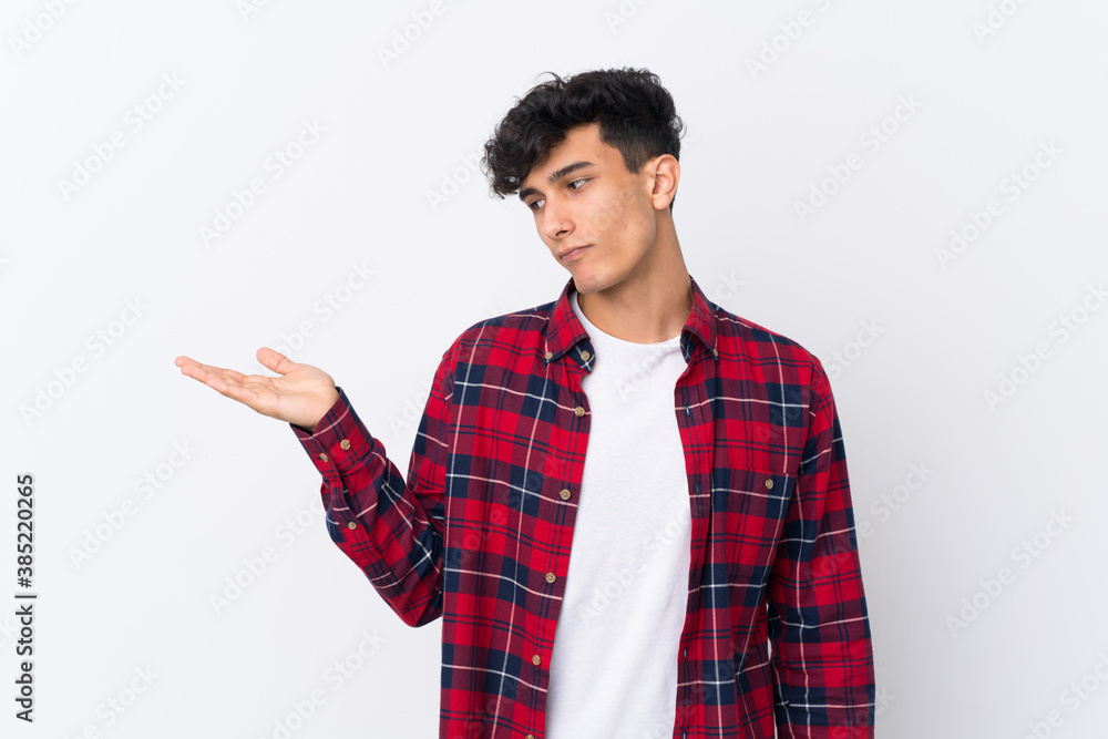 Young Argentinian man over isolated white background holding copyspace with doubts Young Argentinian man over isolated white background holding copyspace with doubts