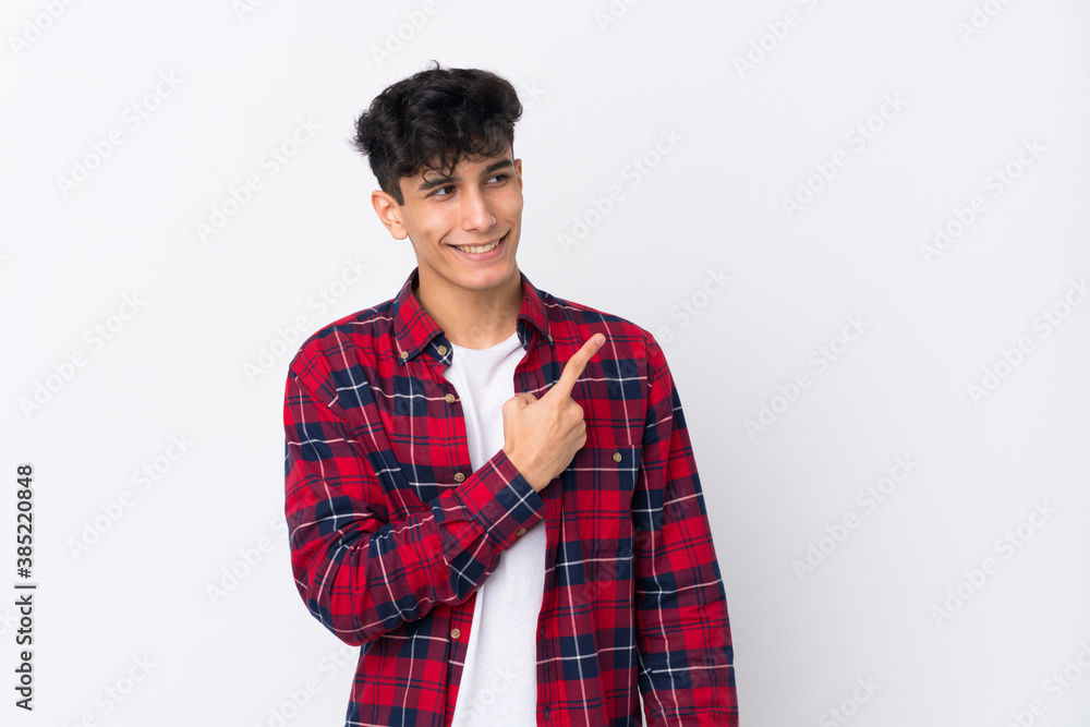 Young Argentinian man over isolated white background pointing to the side to present a product Young Argentinian man over isolated white background pointing to the side to present a product