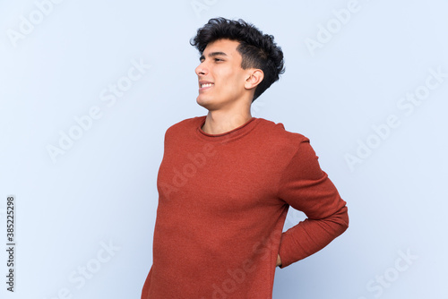 Young Argentinian man over isolated blue background suffering from backache for having made an effort