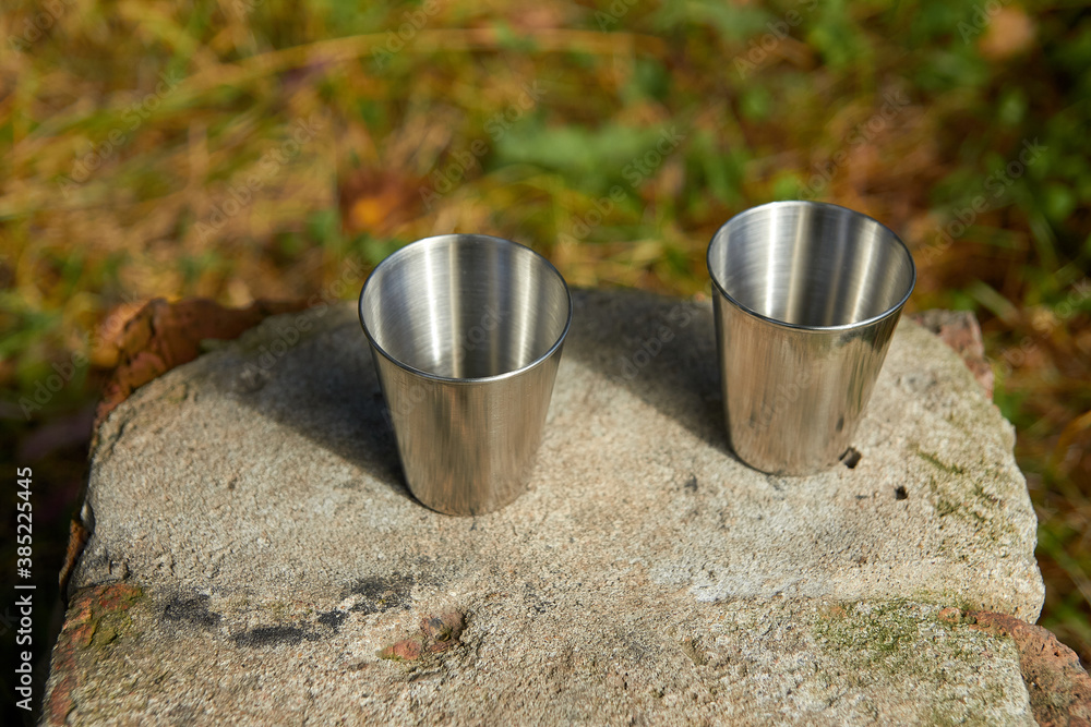 Metal cups for strong alcohol stand on a stone. Metal cups for strong alcohol stand on a stone.